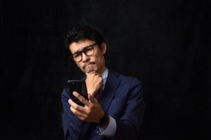 スマホを見て悩む男性